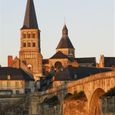 Le clocher de l'église prieurale vue du faubourg au coucher du Soleil